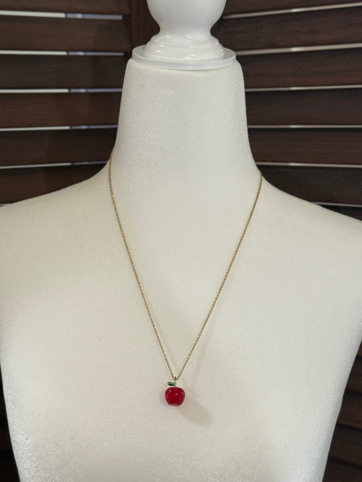 Necklace with a red pendant on a mannequin bust against a wooden background