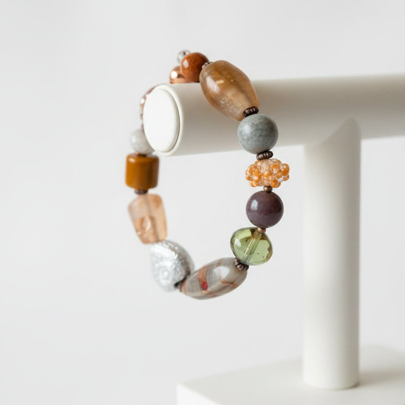 A beaded stretch bracelet featuring a variety of colorful, textured stone and glass beads in earthy tones.