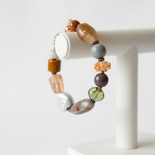 A beaded stretch bracelet featuring a variety of colorful, textured stone and glass beads in earthy tones.