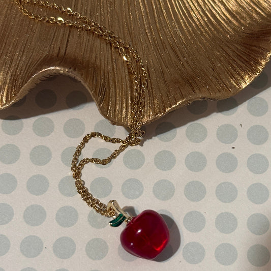 Necklace with a red apple pendant on a polka dot background
