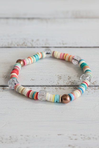 A beaded stretch bracelet with colorful striped beads and clear faceted beads