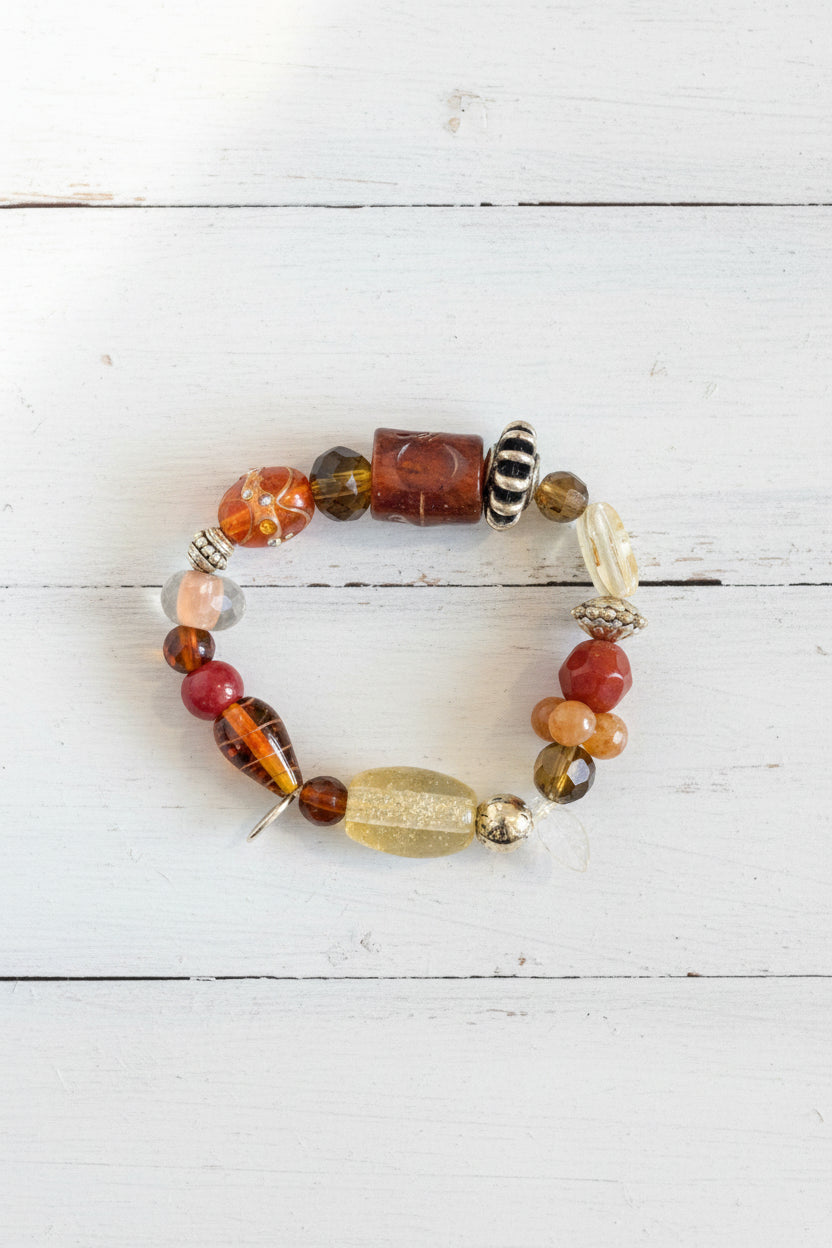 A beaded bracelet featuring a mix of orange, brown, black, white, and clear glass beads.