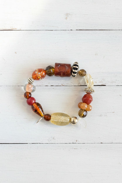 A beaded bracelet featuring a mix of orange, brown, black, white, and clear glass beads.