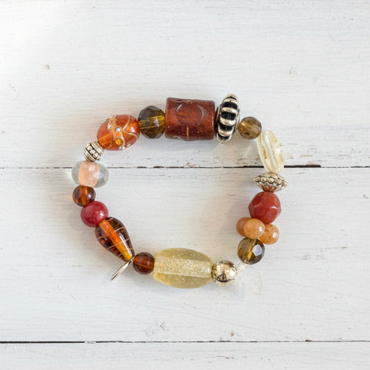 A beaded bracelet featuring a mix of orange, brown, black, white, and clear glass beads.