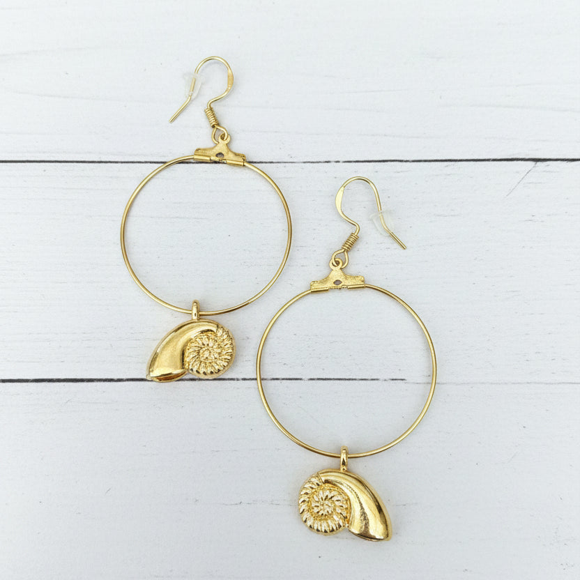 A pair of gold hoop earrings with textured shell charms, displayed on a white background.
