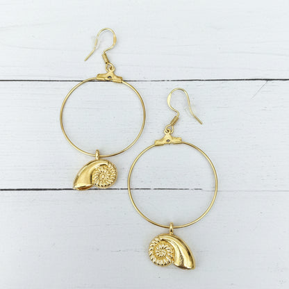 A pair of gold hoop earrings with textured shell charms, displayed on a white background.