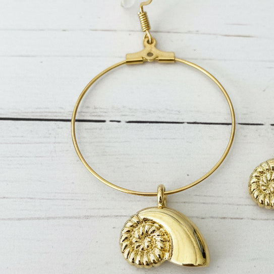 Gold hoop earring with a polished shell-shaped pendant,